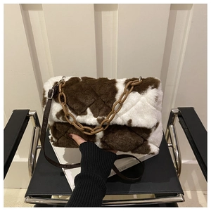 Détail du sac enveloppe en peluche à motif vache avec texture matelassée et chaîne résine