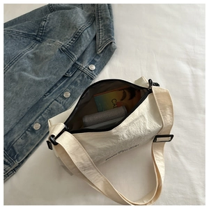 Close-up of lightweight nylon crossbody bag in off-white with smooth zipper closure