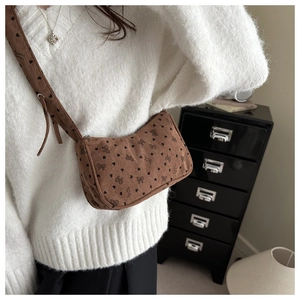 Brown corduroy crossbody bag with black heart and bow pattern on a white sweater
