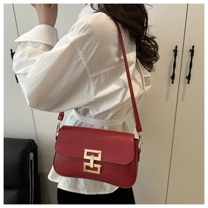 Detail of red leather crossbody bag with oversized gold geometric buckle and strap