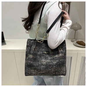 Detail of the glittering grey tote bag with gold chain link and leather shoulder strap