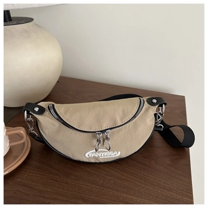 Détail du sac banane en toile kaki avec fermetures éclair argentées sur fond bois