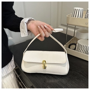 Detail shot of the white crocodile embossed texture and golden metal buckle on the baguette bag