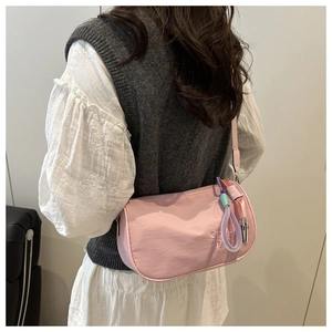 Sac polochon rose en nylon avec broderie porté à l'épaule par un mannequin chic