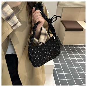 Detail of black fabric shoulder bag featuring white heart patterns and scrunchie strap