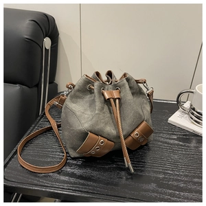 Detail of grey canvas bucket bag with brown leather drawstring and metal eyelets