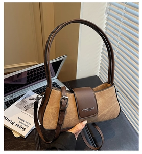 Close-up of minimalist brown leather and canvas shoulder bag with adjustable metal buckle
