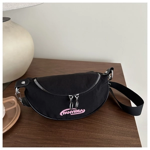 Détail du sac banane croissant noir avec broderie rose sur table en bois