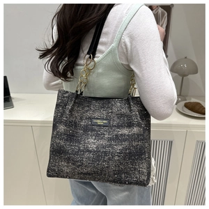 Detail of black glitter tote bag with metallic chain strap worn on the shoulder