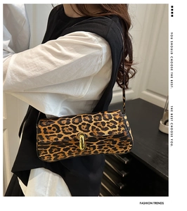 Detail of leopard print underarm bag with gold U-shaped buckle on female model