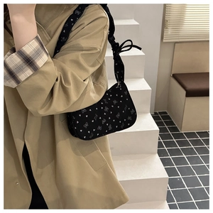 Detail of black pleated shoulder bag featuring white butterfly print and bow strap details
