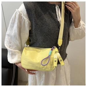 Détail du sac bandoulière en nylon jaune avec broderie CHOU et sangle tissée colorée