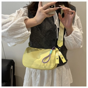 Détail du sac demi-lune en nylon jaune vif avec large bandoulière et broderie