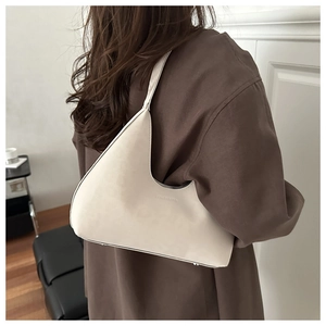Close-up of minimalist beige matte faux leather hobo bag with embossed lettering detail