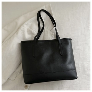 Flat lay of a classic black tote bag showing premium matte leather texture and stitching