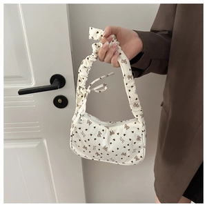 Close-up of beige corduroy small square bag with brown heart and bow patterns