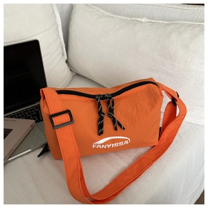 Detail of bright orange nylon crossbody bag with dual zippers and adjustable strap