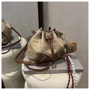 Detail of khaki canvas bucket bag with brown leather drawstring and cute bear charm