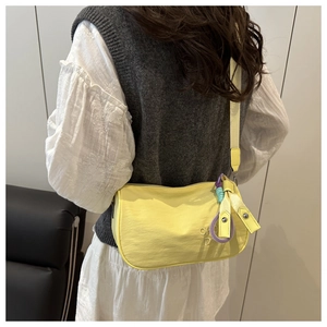 Détail du sac bandoulière en nylon jaune avec broderie et pendentif tissé coloré