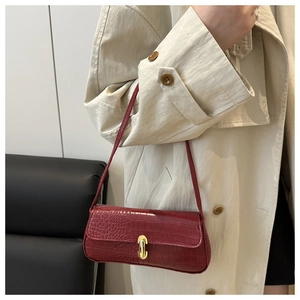 Detail of red faux crocodile pattern baguette bag with a gold capsule turn-lock closure