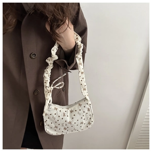 Detail of a beige corduroy mini bag with brown heart patterns and a pleated handle