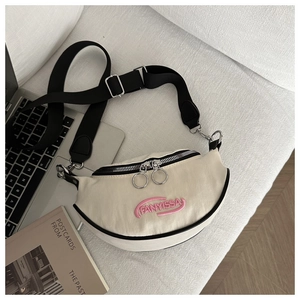 Détail du sac croissant en nylon crème avec broderie FANYISSA et doubles fermetures éclair