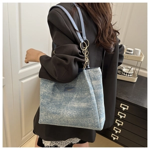 Detail of blue denim tote bag with leather gold chain strap on professional office outfit