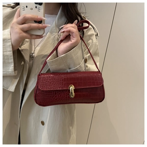 Close-up of deep red crocodile pattern baguette bag with a golden U-shaped metal buckle
