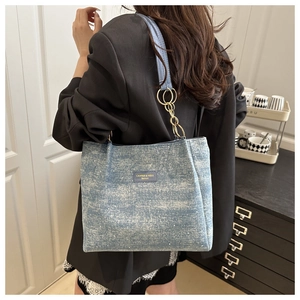 Detail of light blue denim tote with snowflake finish and gold chain strap