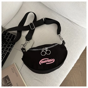 Détail du sac bandoulière en toile noire avec broderie rose et double fermeture éclair argent