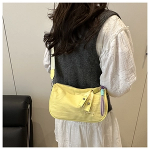 Détail d'un sac oreiller en nylon jaune avec broderie et large bandoulière