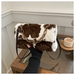 Détail du sac bandoulière en peluche à motif vache, texture fausse fourrure et chaîne