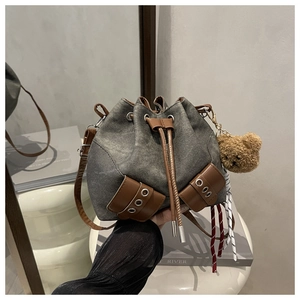 Detail of vintage gray canvas bucket bag with brown leather drawstring and teddy bear charm