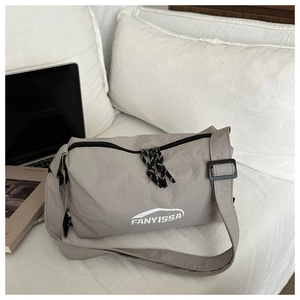 Detail of grey nylon crossbody bag with zipper and FANYISSA text on white bedding