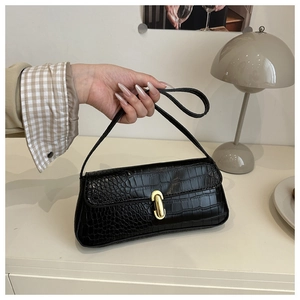 Detail of black crocodile texture shoulder bag with elegant gold metal buckle