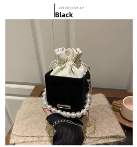 Dettaglio della borsa a secchiello nera vintage con manico di perle e catena d'oro