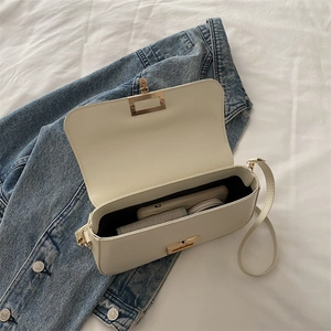 Chic beige crossbody bag with gold buckle and chain strap on blue denim cloth