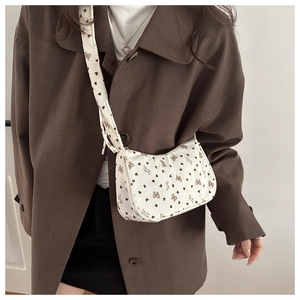 Detail of white corduroy crossbody bag featuring brown hearts and bowknot patterns