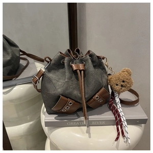 Detail of drawstring bucket bag with canvas fabric and brown leather trim accents