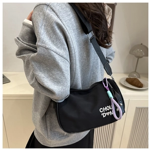 Détail du sac demi-lune en nylon noir avec broderie de cœur et pompon violet