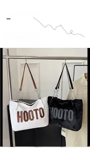 Detail of plush tote bags with HOOTO lettering and metal chain shoulder straps