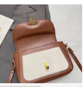 Detail of two-tone crossbody bag with gold twist lock and smooth faux leather finish