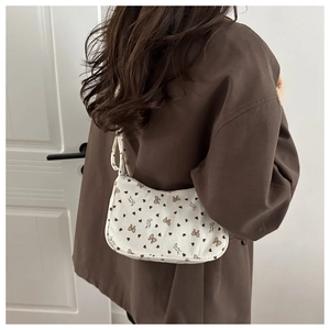 Detail of corduroy shoulder bag with brown heart and bow patterns worn by a model