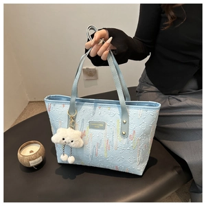 Dettaglio della borsa tote azzurra con ricamo e ciondolo a forma di nuvola