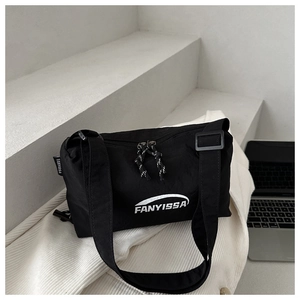 Detail of minimalist black nylon crossbody bag with dual zippers and adjustable wide strap