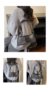 Close-up of a dark grey stone-textured baguette bag with black leather shoulder strap