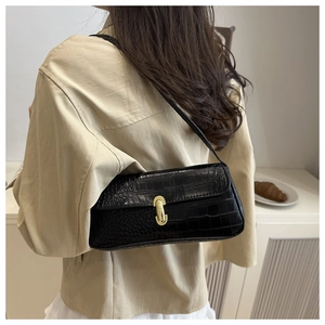 Detail of black crocodile pattern baguette bag featuring elegant gold square twist lock