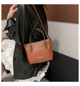 Detail of brown lychee texture leather bucket bag with silver Fashion lettering logo