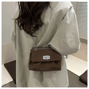 Close-up of brown suede crossbody bag featuring pleated design and silver rhinestone clasp
