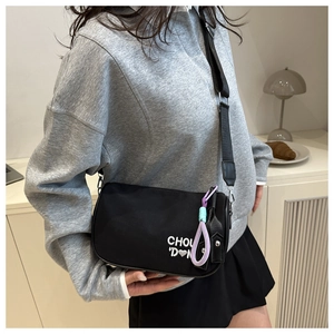 Détail du sac bandoulière noir avec broderie blanche et décoration de sangle colorée